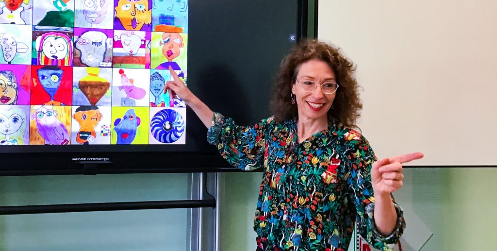 Kunstlehrerin Jana Bens-Wiewiórski erklärt an einem Whiteboard sprechende Portraits.